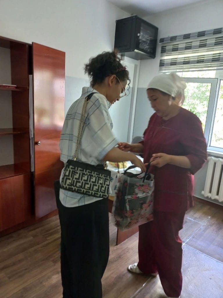 GYxC volunteer handing over a donation bag to hospital staff in Uzbekistan