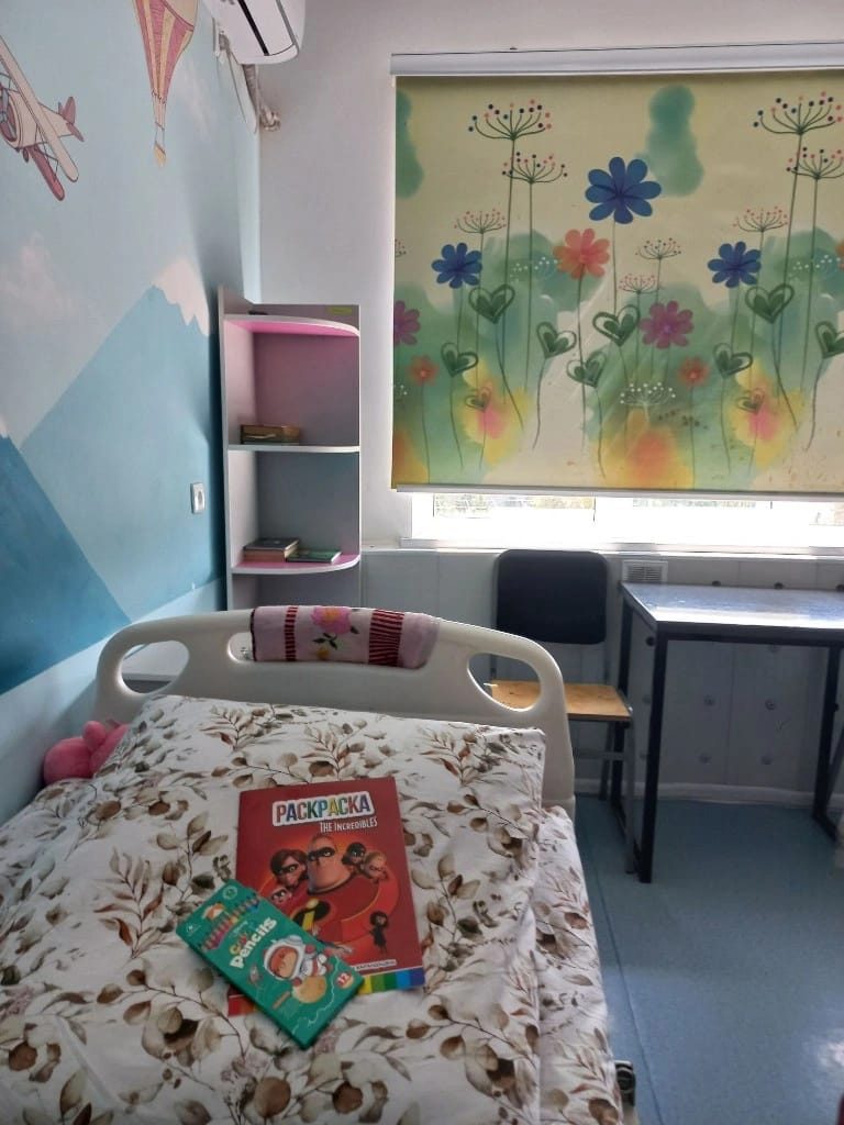 A decorated children's hospital room with books on the bed